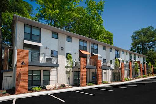 A row of modern townhouses with a paved road in front.