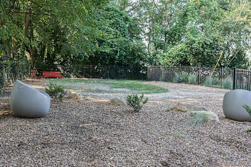 A garden with two large spherical objects and a red bench.