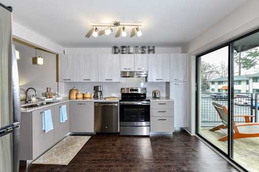 A modern kitchen with white cabinets and a wooden floor.