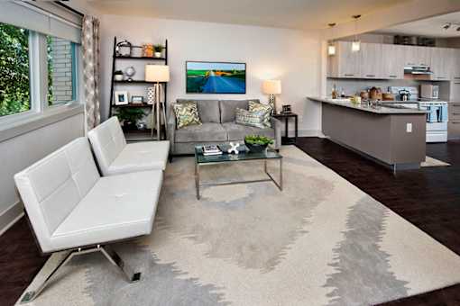 A living room with a white couch and a glass coffee table.