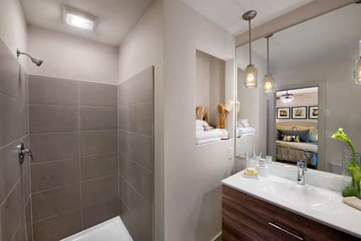 A bathroom with a white sink and a shower with a glass door.