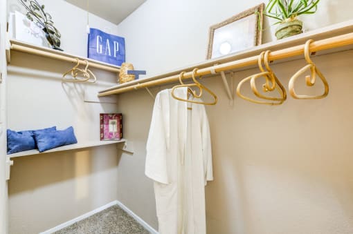 a walk in closet with a white robe and gold hangers