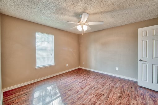 an empty living room with a ceiling fan and wood floors