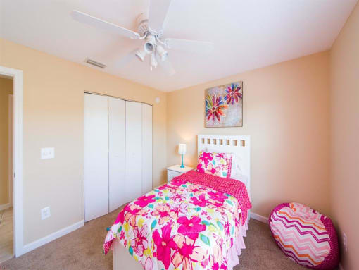 Furnished model bedroom with carpet flooring, multi speed ceiling fan, large closet, and wall art