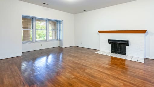Living room with fireplace, windows, and hardwood flooring