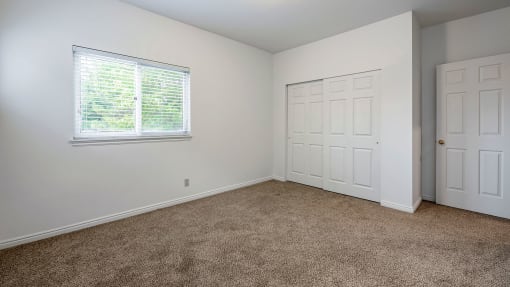 Bedroom with window, carpet flooring, and closet space