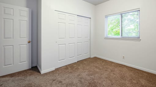 Bedroom with white walls, carpet flooring, a window, and a closet