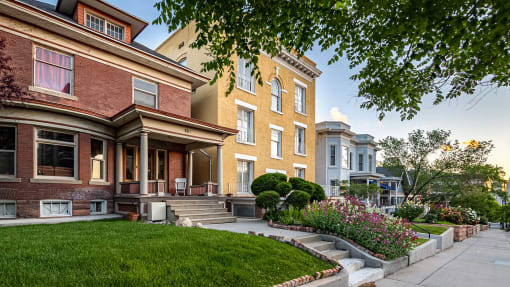 Front exterior of red brick home next to a yellow home for First Avenue Homes