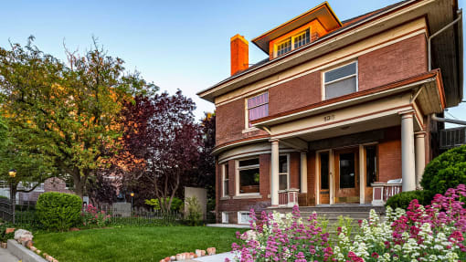 Side exterior view of red brick First Avenue Home with flowers in front of it