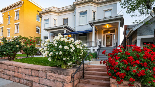 Side view exterior of light blue First Avenue Home with flowers in front yard