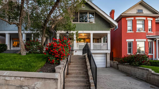 Front exterior view of green First Avenue home with a rose bush
