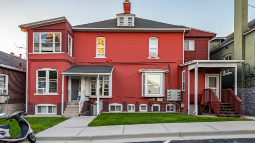 Front exterior of red First Avenue Homes with a view of the front yard