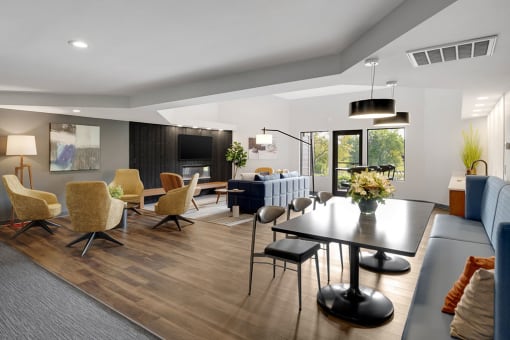 Resident lounge with gathering table and seating surrounding a TV mounted above a fireplace