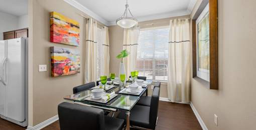 Spacious dining room with wood grain plank flooring, oversized windows, spacious kitchen with white appliances and side by-by-side refrigerators The Lanesborough Apartments in Houston.