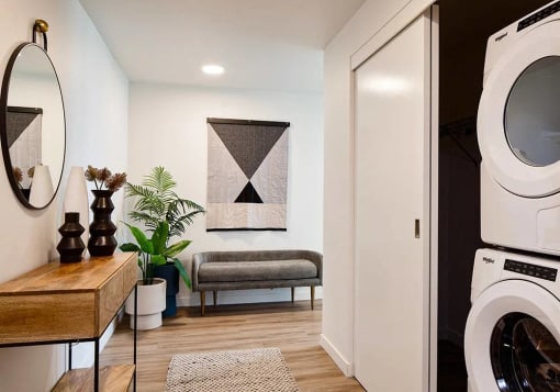 Entry foyer with washer and dryer in a closet with small bench and table and mirror