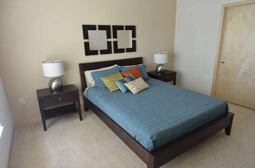 A bed with a blue comforter and a lamp on a side table.