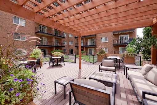 A wooden patio with a pergola and furniture.