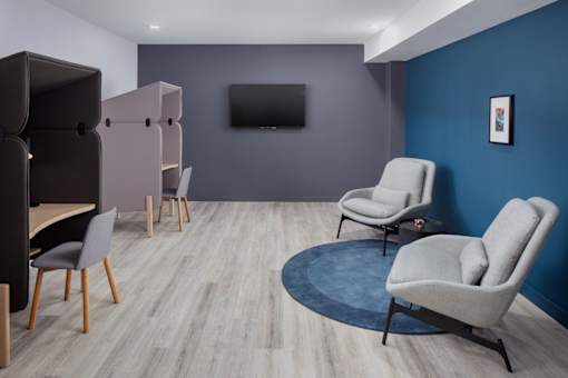 A living room with a grey sofa and a television on the wall.
