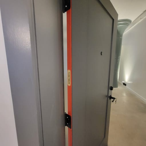 A grey door with a red stripe on the side is closed.
