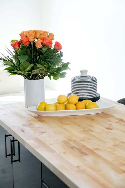 A vase of flowers sits on a table with lemons.