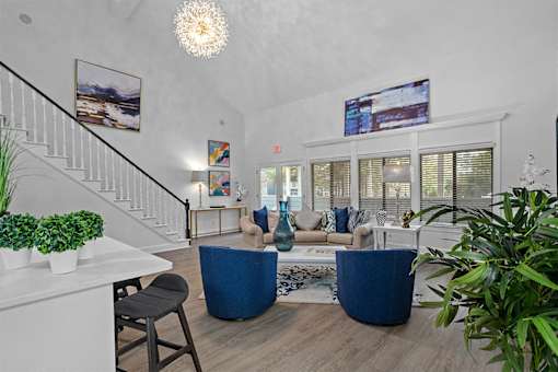 A living room with a staircase and a blue sofa.