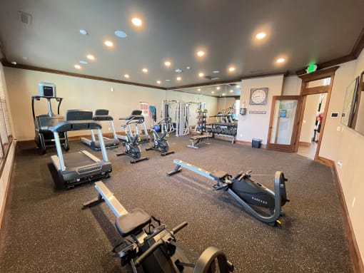 a gym with cardio equipment and weights on the floor