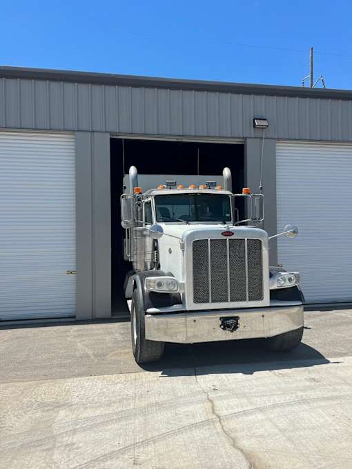 A semi truck is parked in front of a grey building.