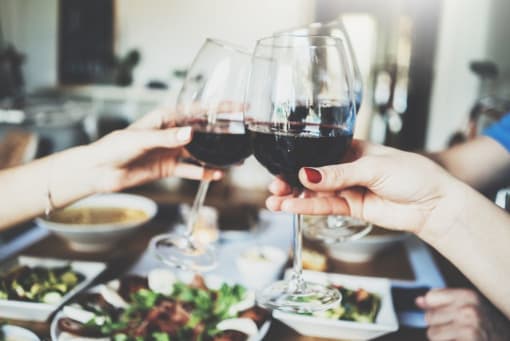 two people holding wine glasses over a table of food