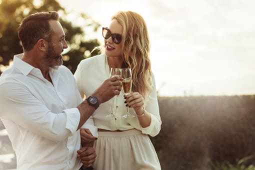 a man and woman holding wine glasses and looking at each other