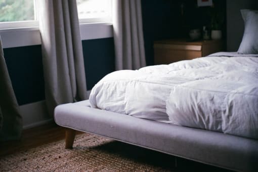 a bed with a white comforter and pillows on it