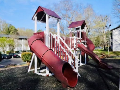 a playground with a red slide and a white playset at Uphill Flats, Decatur, GA