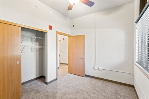 a bedroom with a large closet, illuminated ceiling fan, and a window letting in natural light