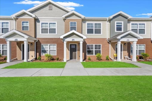 The individual portico entrances and well-kept sidewalk and lawn at Muskego School Apartments