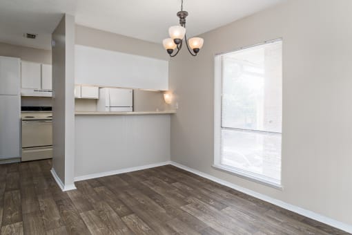 A kitchen with white cabinets and a window with blinds.