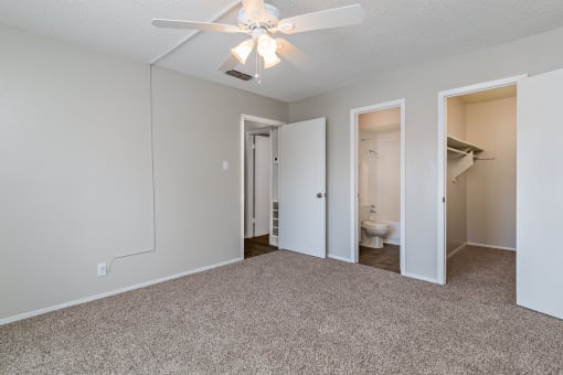 A room with a ceiling fan and carpeted floor.