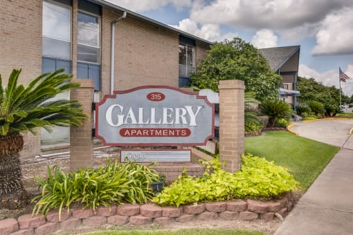 A sign for Gallery Apartments is in front of a building.