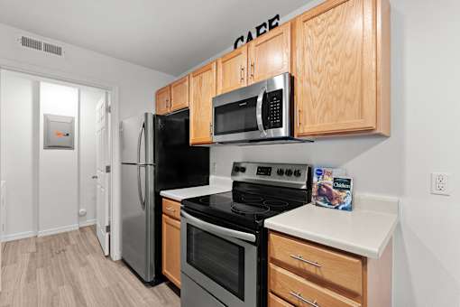 Kitchen with wooden cabinetry, plank flooring, and sleek appliances at Eagles Landing, Ammon, ID, 83406