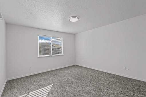 Expansive bedroom with plush carpeting and window at Eagles Landing, Ammon, 83406
