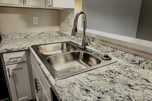 A kitchen sink with a granite countertop and a faucet.