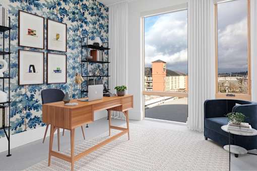 A room with a desk, a chair, and a wall with pictures on it at The Fitz Apartments, Portland, OR