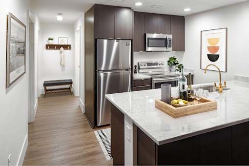 A modern kitchen with a refrigerator, oven, and sink at The Fitz Apartments, Portland