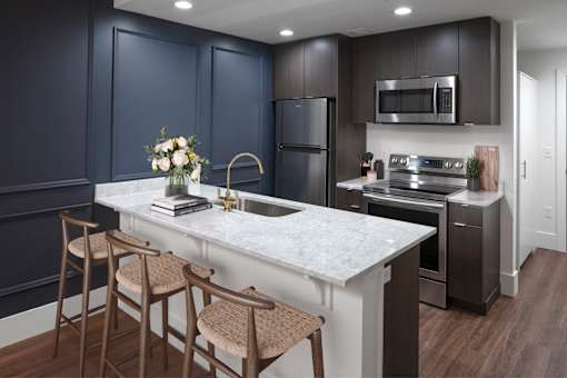A kitchen with dark blue cabinets and a white marble countertop at The Fitz Apartments, Oregon
