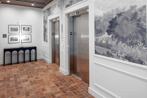 A hallway with two elevators and a wall with a painting on it at The Fitz Apartments,Oregon 97210