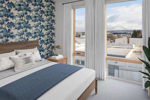 A bedroom with a large bed and a view of a bridge at The Fitz Apartments, Portland, OR