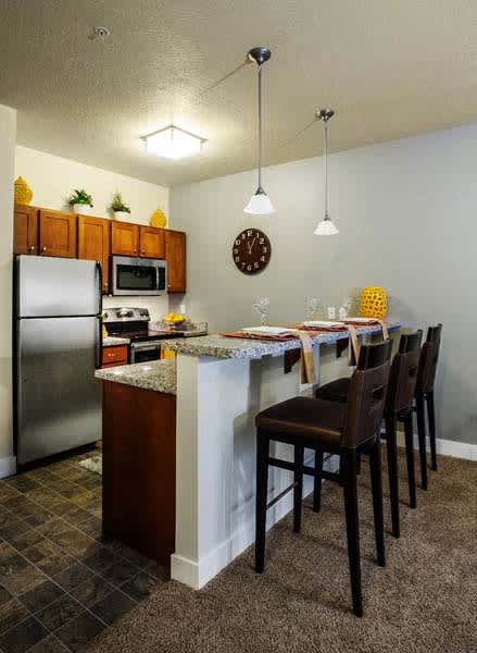 Liberty Gateway Apartments, Salt Lake City, Utah, kitchen with bar seating, refrigerator, microwave, oven, and a clock on the wall.