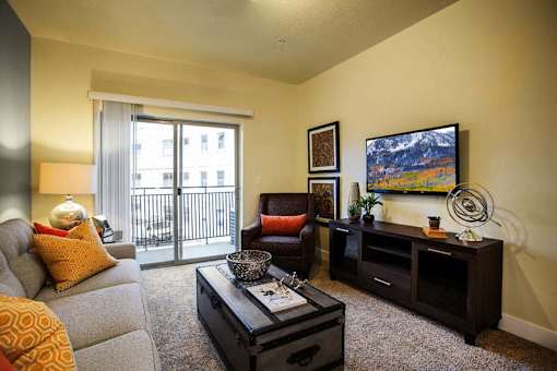 Liberty Gateway Apartments, Salt Lake City, Utah, living room with a grey couch, a red chair, a black coffee table, and a painting on the wall.