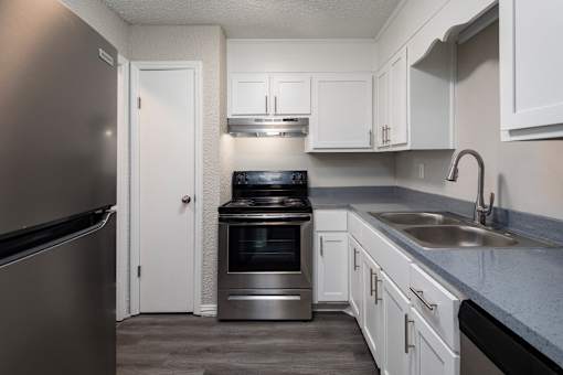 A kitchen with a refrigerator, oven, and sink.