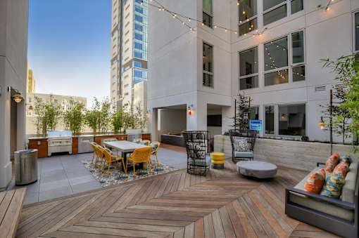 A wooden deck with a table and chairs is surrounded by buildings.