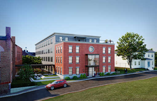 A red car is parked on the side of a road in front of a building.