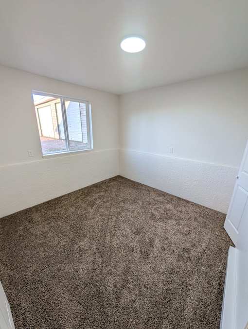 A room with a carpeted floor and a window.